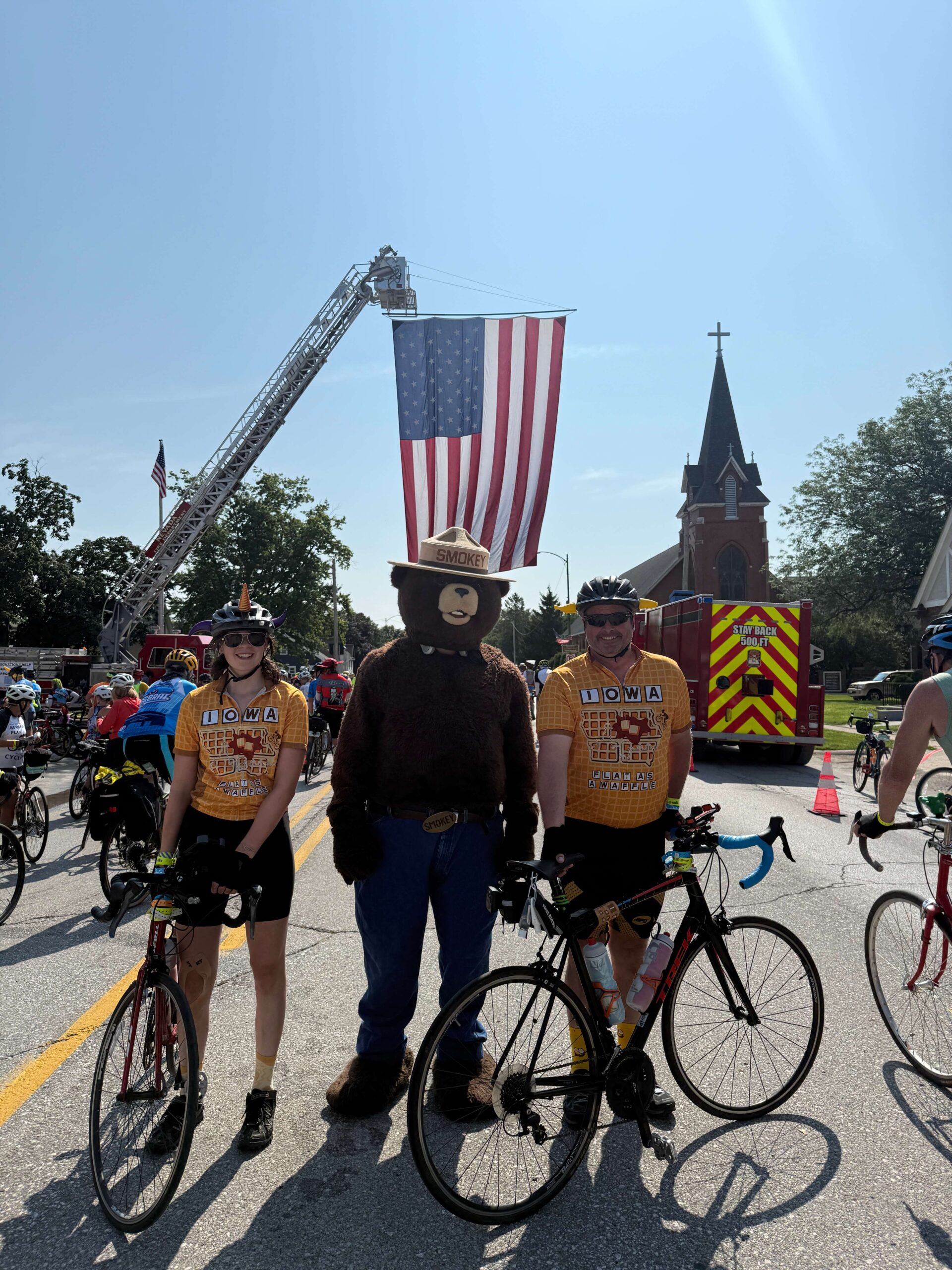 RAGBRAI cyclists gathered with their bicycles beneath USA flag