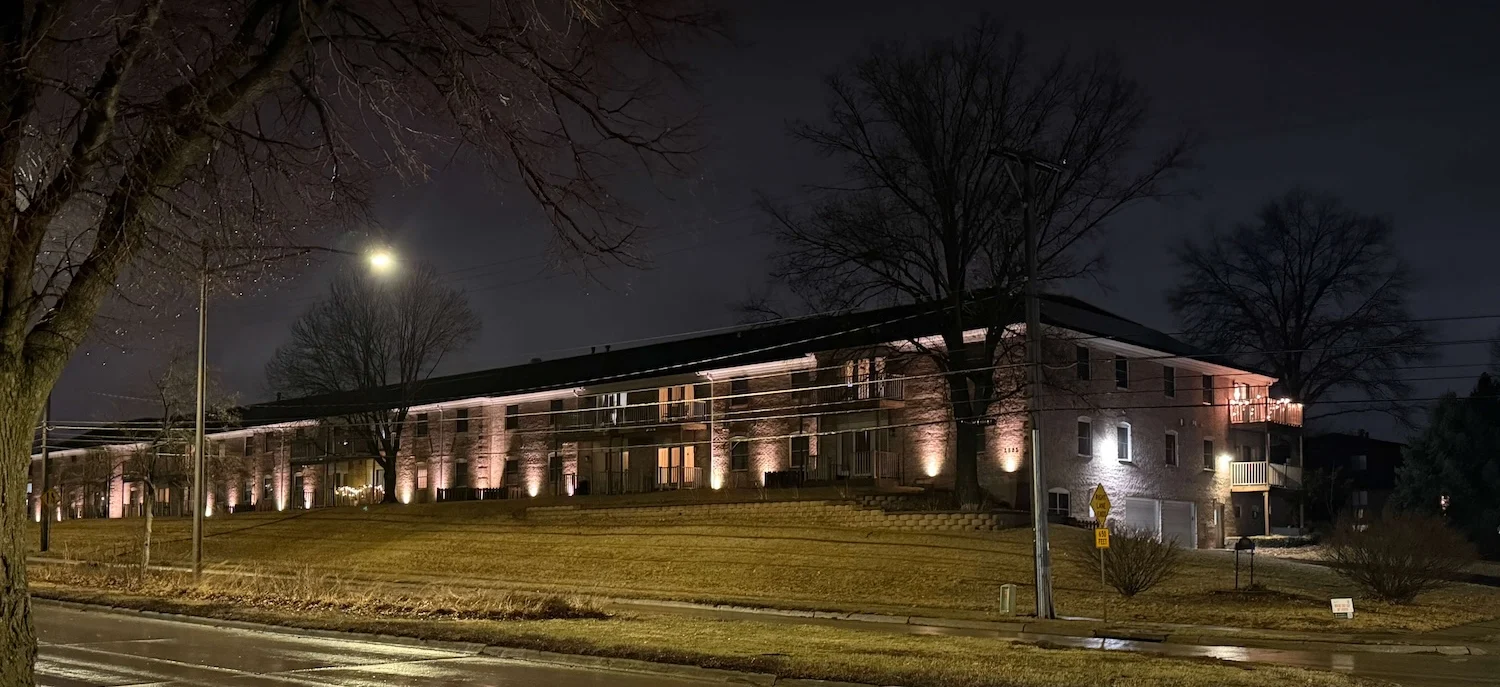 Warmly lit entrance at Cambridge Place Apartments in Iowa City, welcoming residents home at dusk.